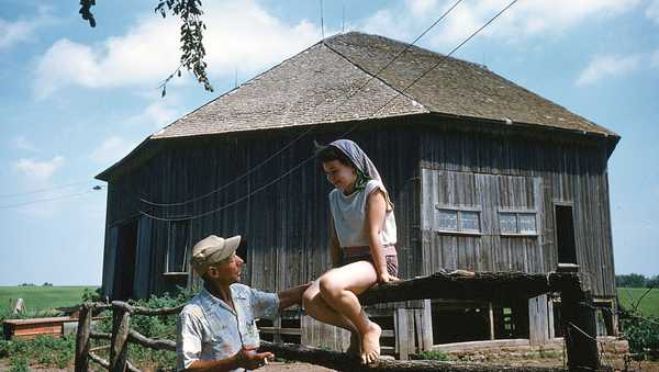 DELTA, IOWA - AUGUST 1958: A girl sits on a fence talking to her dad on a hot day in Delta,Iowa. (Photo by Ivan Dmitri/Michael Ochs Archives/Getty Images)