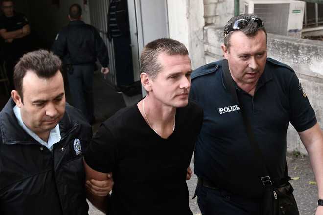 Russian Alexander Vinnik (C) is escorted by police officers as he arrives at a courthouse in Thessaloniki on October 4, 2017. 
Alexander Vinnik, who headed BTC-e, an exchange he operated for the Bitcoin crypto-currency, was indicted by a US court in late July on 21 charges ranging from identity theft and facilitating drug trafficking to money laundering. Moscow has requested the extradition of Russian national also wanted in the United States for laundering billions of dollars through a Bitcoin exchange he operated. / AFP PHOTO / SAKIS MITROLIDIS        (Photo credit should read SAKIS MITROLIDIS/AFP via Getty Images)