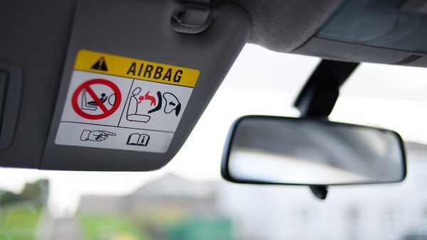 Image showing a sun-visor in the down position in a car, revealing Airbag Safety information.