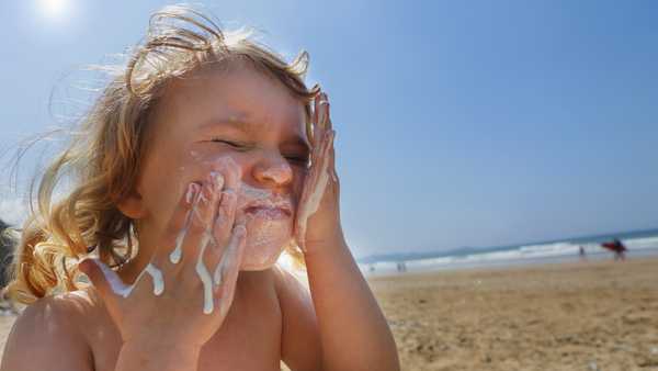 toddler girl applying suncream