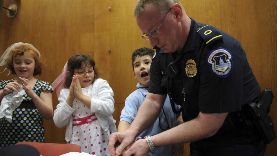 Gabriel Ayoud, 8, gets fingerprinted by Capitol Police Officer Howard Liebengood as sisters Sophia, 8, washes the ink off and Amina, 8, waits her turn during "Kid Safety Day," held in Dirksen, April 24, 2008.
