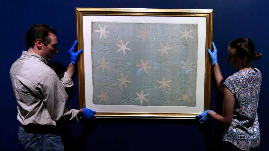 Collections manager Michelle Moskal, right, and curator Mark Turdo hang the Commander-in-Chief's Standard, Wednesday, June 13, 2018, at an exhibition gallery in the Museum of the American Revolution in Philadelphia. The faded and fragile blue silk flag marked General George Washington's presence on the battlefield during the Revolutionary War. The museum is bringing the flag out of its archives for public viewing on Thursday, June 14, Flag Day, until Sunday. Its appearance at the museum is the flag's first public display in Philadelphia since the war.