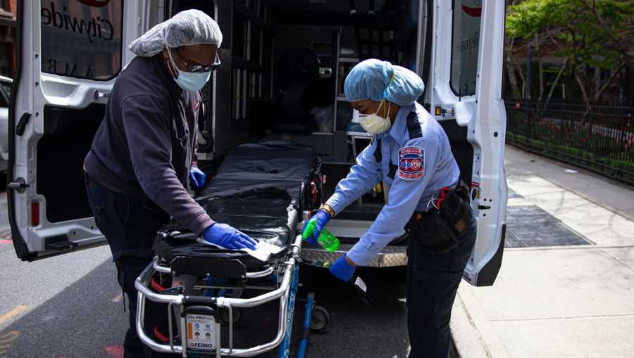 Two emergency medical staff of a private ambulance company sanitize a hospital gurney after they dropped off a patient at the Cobble Hill Health Center April 20, 2020 in the Brooklyn borough of New York City.