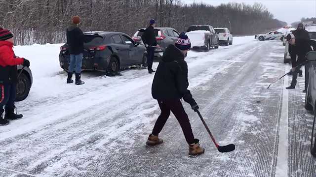 Travelers pass hockey puck while waiting for a road to clear