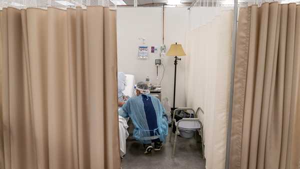 A physical therapist works with a patient at a field hospital operated by Care New England set up in a former bank call center to handle a surge of COVID-19 patients in Cranston, R.I, Dec. 14, 2020.