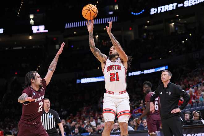 Houston guard Emanuel Sharp (21) shoots over Texas A&amp;amp;M guard Pop Isaacs (2) as Texas A&amp;amp;M head coach Bucky McMillan, right, watches during the first half in the second round of the NCAA college basketball tournament Saturday, March 21, 2026, in Oklahoma City.