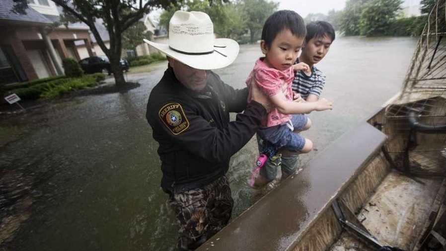 ​Fort Bend County Sheriff Troy Nehls and Lucas Wu lift Ethan Wu into an airboat as they are evacuated from rising waters.