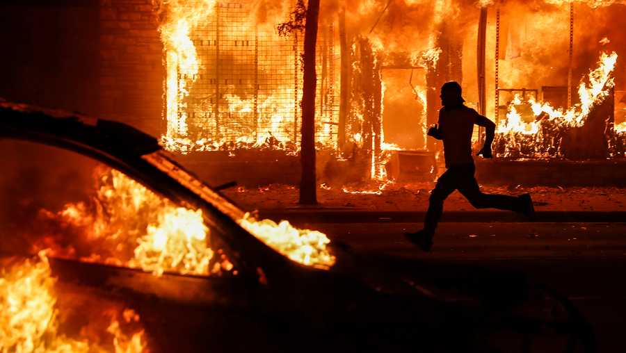 A protester runs past burning cars and buildings on Chicago Avenue, Saturday, May 30, 2020, in St. Paul, Minn. Protests continued following the death of George Floyd, who died after being restrained by Minneapolis police officers on Memorial Day.