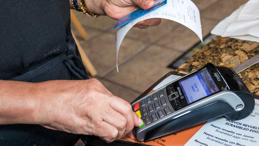 A person is shown pressing a credit card scanner and holding a card and receipt.