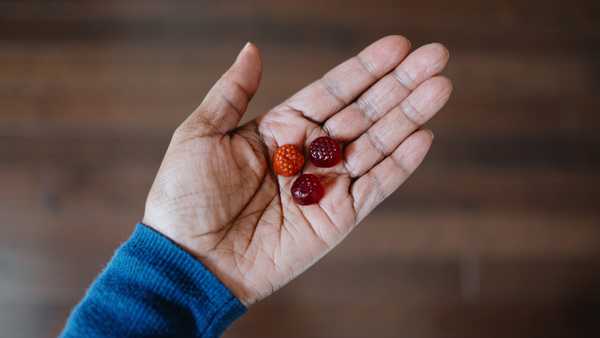 High angle view of unrecognizable woman's hand holding fruit-flavored gummy nutritional supplements