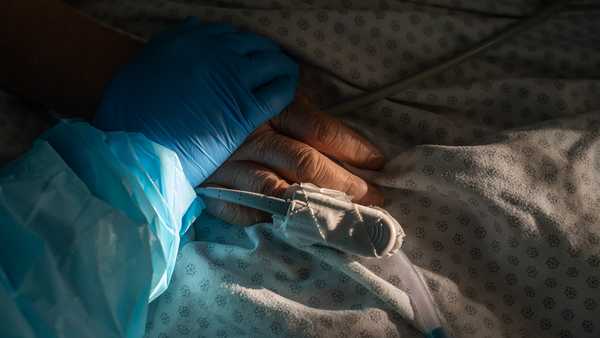 Medical staff member Tanna Ingraham holds the hand of a patient. (Photo by Go Nakamura/Getty Images)