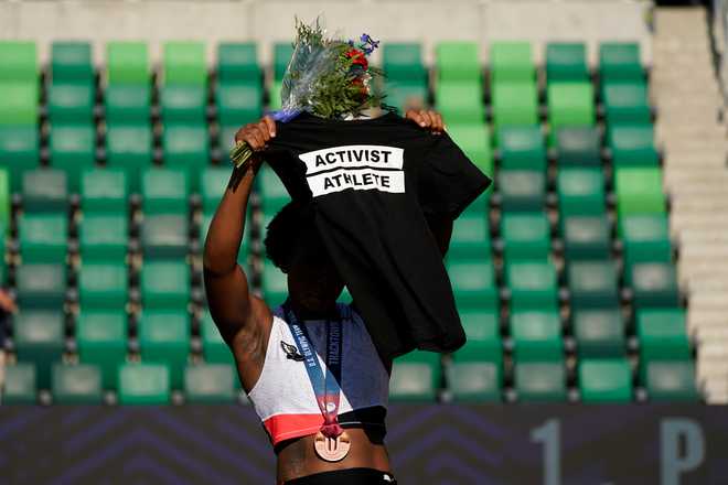 Gwendolyn Berry her Activist Athlete T-Shirt over her head during the metal ceremony after the finals of the women's hammer throw at the U.S. Olympic Track and Field Trials Saturday, June 26, 2021, in Eugene, Ore. Berry finished third.