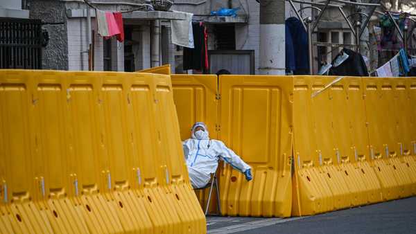 A worker, wearing protective gear, guards the entrance to a neighborhood in lockdown in Shanghai, China, on March 29.