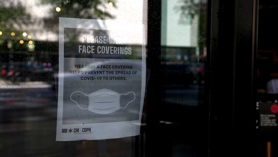 A sign encouraging customers to wear protective masks is displayed in the window of a shop along Michigan Avenue in Chicago, Illinois, U.S., on Friday July 24, 2020.