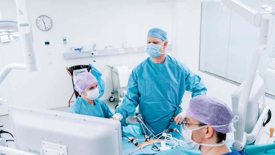 Male and female doctors performing gastric bypass surgery. Medical professionals are in operating room. They are in protective workwear.