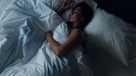 Young beautiful girl or woman sleeping alone in big bed at night, top view