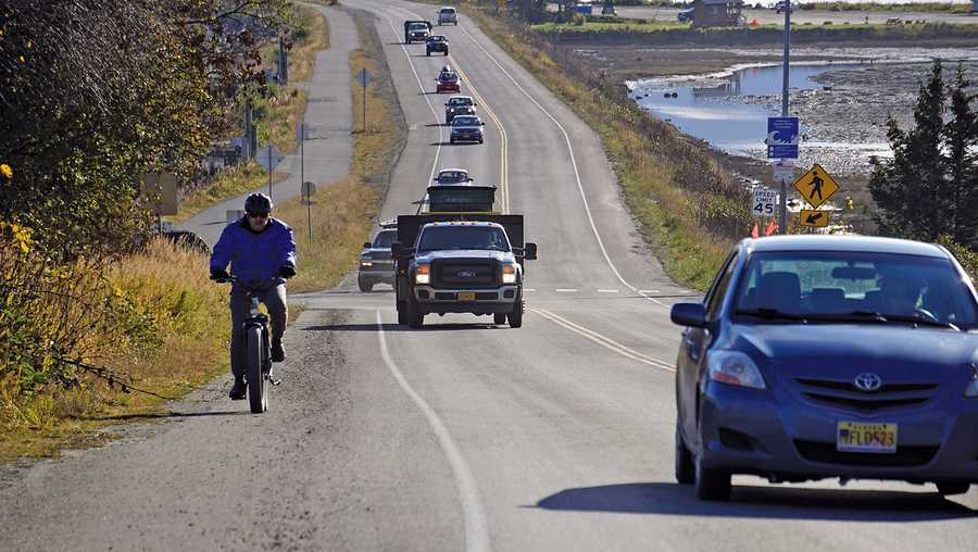 A biker leads a line of cars driving off the Homer Spit at about on Monday, Oct. 19, 2020, in Homer, Alaska after a tsunami evacuation order was issued for low-lying areas in Homer.
