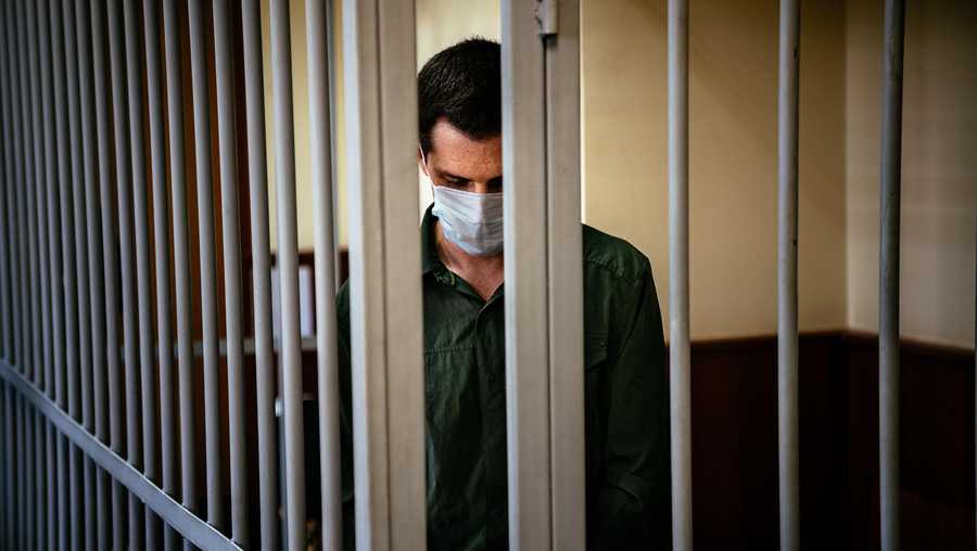 TOPSHOT - US ex-marine Trevor Reed, charged with attacking police, stands inside a defendants' cage during his verdict hearing at Moscow's Golovinsky district court on July 30, 2020. - A Russian court on February 10, 2021 ordered a psychological examination of former US Marine Trevor Reed, who was convicted of assaulting a police officer in a case condemned by President Joe Biden's administration. Reed, 29, was found guilty and sentenced to nine years behind bars in July last year for allegedly hitting a Moscow law enforcement officer while drunk in 2019.