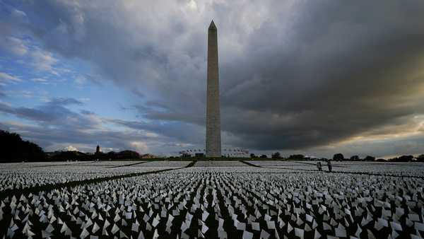 FILE - In this Sept. 17, 2021, file photo, with the Washington Monument in the background, people look at white flags that are part of artist Suzanne Brennan Firstenberg's temporary art installation, 