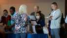 SUNRISE, FLORIDA - FEBRUARY 23: Giselle Delgado (2nd R) and Sam Nasr (R) visit the Pharmsource, Llc booth to see what jobs are available during the Mega South Florida Job Fair held in the FLA Live arena on February 23, 2023 in Sunrise, Florida. Florida job fair