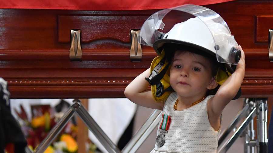 HORSLEY PARK, SYDNEY - JANUARY 07: Charlotte O'Dwyer, the young daughter of Rural Fire Service volunteer Andrew O'Dwyer stands in front of her fathers casket wearing his helmut after being presented with her fathers service medal by RFS Commissioner Shane Fitzsimmons during the funeral for NSW RFS volunteer Andrew O'Dwyer at Our Lady of Victories Catholic Church on January 7, 2020 in Horsley Park, Sydney. 