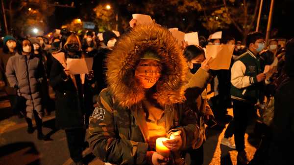 Protesters hold up blank papers and chant slogans as they march in protest in Beijing, Sunday, Nov. 27, 2022.