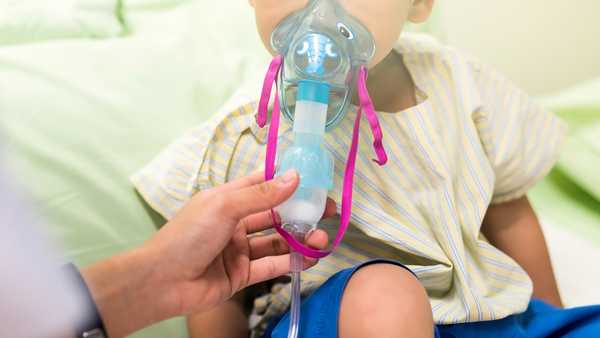 Sick young boy, 3 years old, inhale medication by inhalation mask to cure Respiratory Syncytial Virus (RSV) on hospital bed.