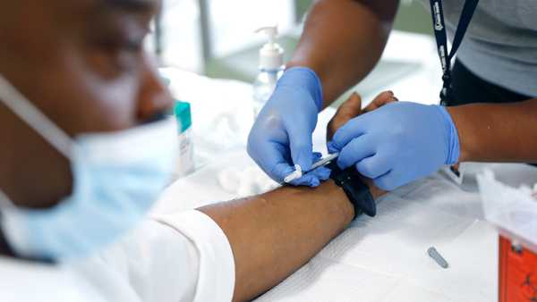 LOS ANGELES, CA - AUGUST 23, 2022: David Hightower, 57, left, looks away while receiving the monkeypox vaccine by registered nurse Jeremy Oyague, right, with The Los Angeles Department of Public Health at a vaccination clinic to immunize people against monkeypox and COVID at The Village Mental Health Services in Los Angeles, a site run by The People Concern. (Christina House / Los Angeles Times via Getty Images)