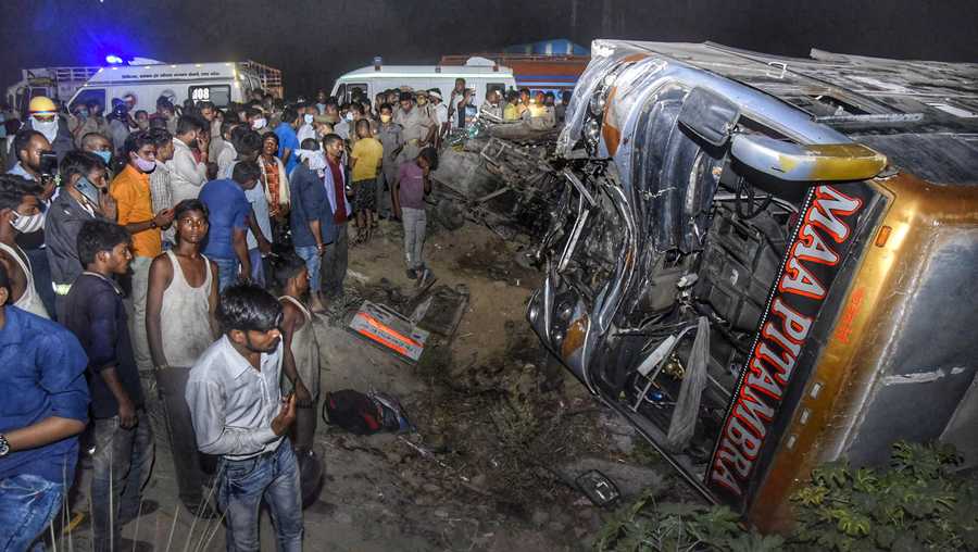 Onlookers gather near the wreckage after a bus carrying migrant workers after the lifting of coronavirus restrictions hit a delivery van on a highway near Kanpur, Uttar Pradesh state, India, Tuesday, June 8, 2021. More than a dozen people were killed.