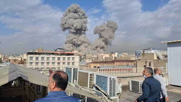 People watch as smoke rises on the skyline after an explosion in Tehran, Iran, Saturday, Feb. 28, 2026