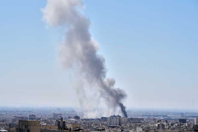 A plume of smoke rises after a strike in Tehran, Iran, Sunday, March 1, 2026.