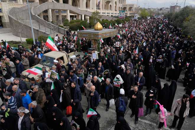 People follow a truck carrying the flag draped coffins of Gen. Ali Mohammad Naeini, a spokesperson for Iran’s paramilitary Revolutionary Guard and one of his comrades Amir Hossein Bidi , during their funeral procession in Tehran, Iran.