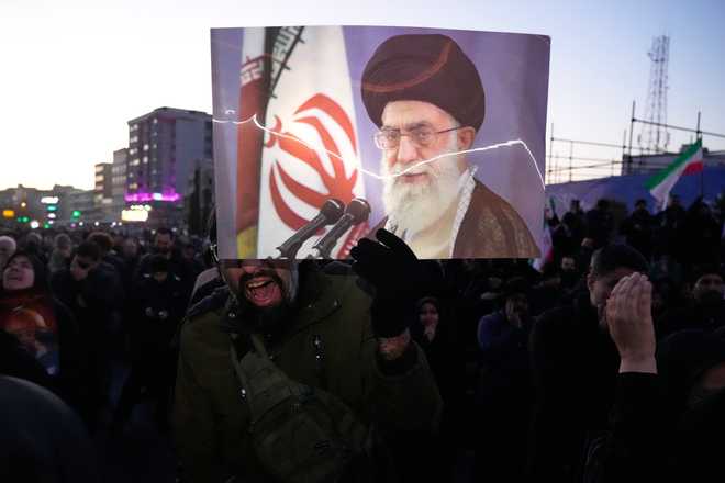 Government supporters mourn in a gathering after state TV officially announced the death of Iranian Supreme Leader Ayatollah Ali Khamenei, shown in the poster, in Tehran, Iran, Sunday, March 1, 2026.