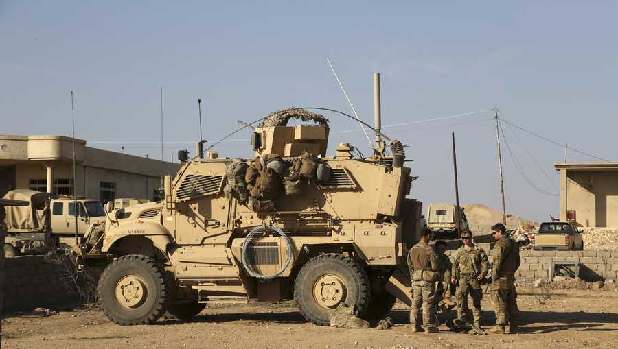 In this Feb. 23, 2017 photo, U.S. Army soldiers stand outside their armored vehicle on a joint base with Iraqi army south of Mosul, Iraq.  Iraqi security officials say 17 Katyusha rockets have hit an Iraqi air base south of the city of Mosul that houses American troops. The two officials say there are no immediate reports of casualties from the attack, which occurred on Friday, Nov. 8, 2019.