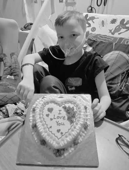 Jace Zembsch poses with a cake that says 'I love you' while in the hospital.