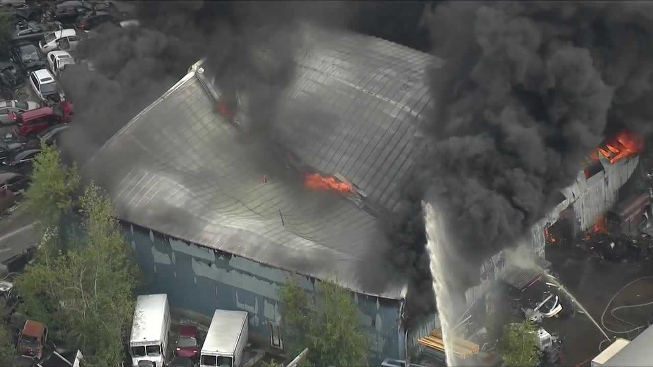 Junkyard fire sends thick plume of black smoke into sky