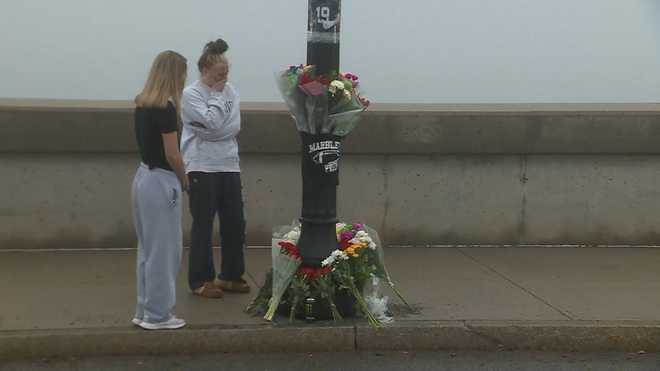 Two women visit a memorial on the causeway in Marblehead, Massachusetts, that s was left in honor of 18-year-old James Galante, a town x20;native who died of injuries he sustained in a road accident.
