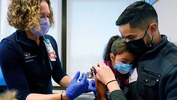 Kidney transplant patient Sophia Silvaamaya, 5, held by her father Pedro Silvaamaya, is vaccinated by nurse Kelly Vanderwende, Wednesday, Nov. 3, 2021, at Children's National Hospital in Washington. The U.S. enters a new phase Wednesday in its COVID-19 vaccination campaign, with shots now available to millions of elementary-age children in what health officials hailed as a major breakthrough after more than 18 months of illness, hospitalizations, deaths and disrupted education. (AP Photo/Carolyn Kaster)