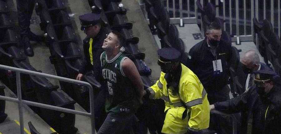 A fan is handcuffed and escorted out of TD Garden by police after allegedly throwing a water bottle at Brooklyn Nets' Kyrie Irving as he left the court after Game 4 during an NBA basketball first-round playoff series, Sunday, May 30, 2021, in Boston. The Nets won 141-126. (AP Photo/Elise Amendola)