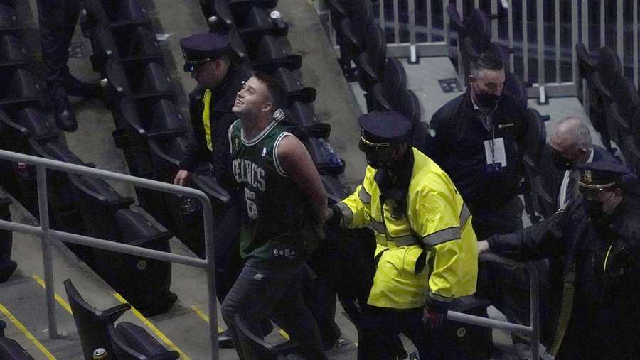 A fan is handcuffed and escorted out of TD Garden by police after allegedly throwing a water bottle at Brooklyn Nets' Kyrie Irving as he left the court after Game 4 during an NBA basketball first-round playoff series, Sunday, May 30, 2021, in Boston. The Nets won 141-126.