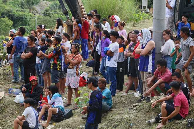 Relatives and others wait for updates after a huge mound of garbage collapsed at a waste segregation facility in Binaliw, Cebu city on Friday, Jan. 9, 2026.