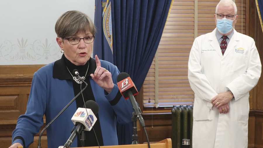Kansas Gov. Laura Kelly discusses the coronavirus pandemic as her health secretary, Dr. Lee Norman, watches behind her at a news conference.