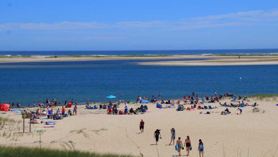 In this file image, beachgoers enjoy a sunny afternoon at Lighthouse Beach in Chatham, Mass.