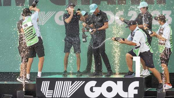 Team champions David Puig, Sebastián Muñoz, Mito Pereira, Captain Joaquín Niemann of Torque GC and their caddies celebrate on stage with the team trophy during LIV Golf DC at the Trump National Golf Club in Washington Sunday, May 28, 2023, in Sterling, Virginia. The most disruptive year in golf ended Tuesday, June 6, 2023, when the PGA Tour and European tour agreed to a merger with Saudi Arabia's golf interests, creating a commercial operation designed to unify professional golf around the world.