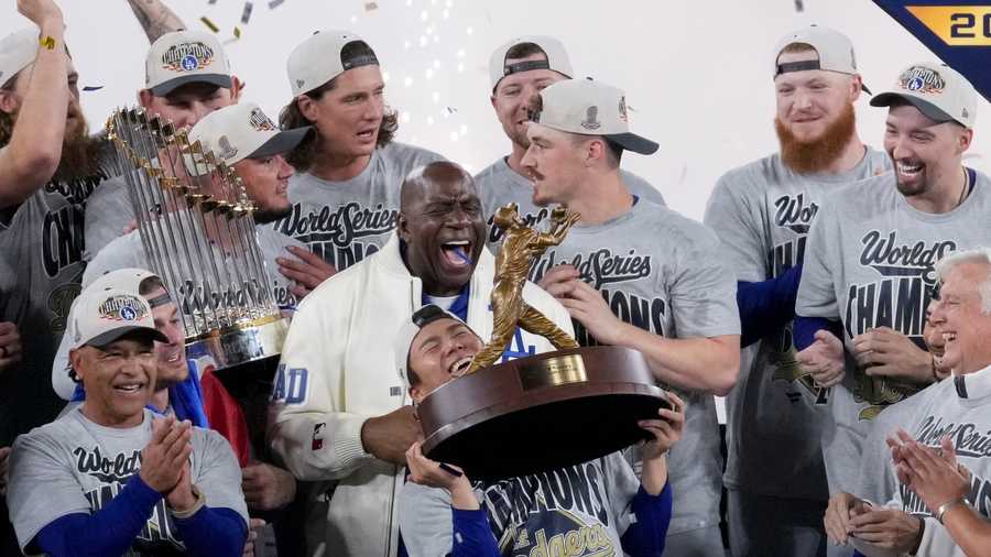 Los Angeles Dodgers World Series MVP Yoshinobu Yamamoto holds his trophy as teammates and owner Magic Johnson celebrate their win in Game 7 of baseball&apos;s World Series against the Toronto Blue Jays, Sunday, Nov. 2, 2025, in Toronto. (AP Photo/Ashley Landis)