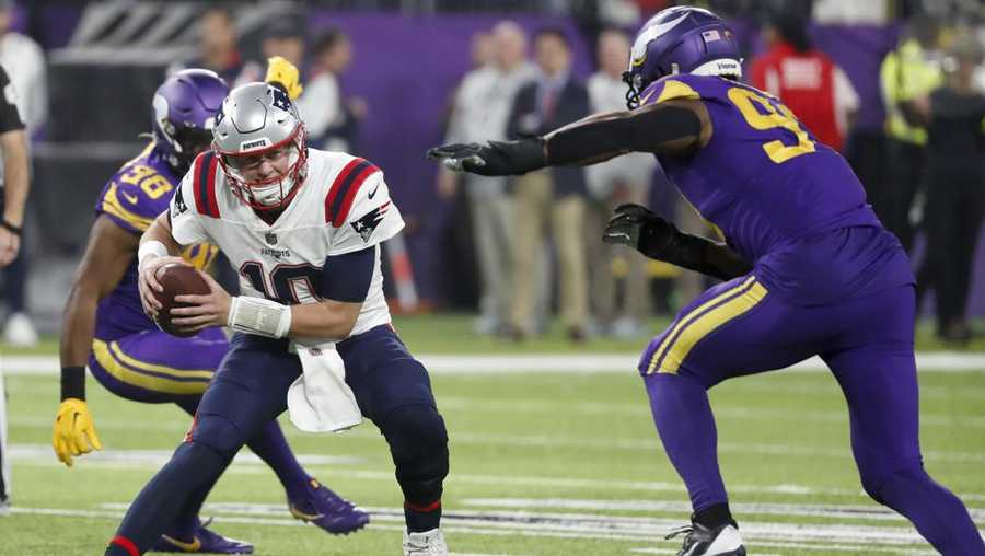 New England Patriots quarterback Mac Jones (10) runs from Minnesota Vikings linebacker Danielle Hunter, right, during the second half of an NFL football game, Thursday, Nov. 24, 2022, in Minneapolis. The Vikings won 33-26.