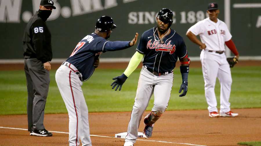 Atlanta Braves' Marcell Ozuna is congratulated by third base coach Ron Washington after hitting a two-run home run during the first inning of the team's baseball game against the Boston Red Sox, Tuesday, Sept. 1, 2020, in Boston. (AP Photo/Mary Schwalm)