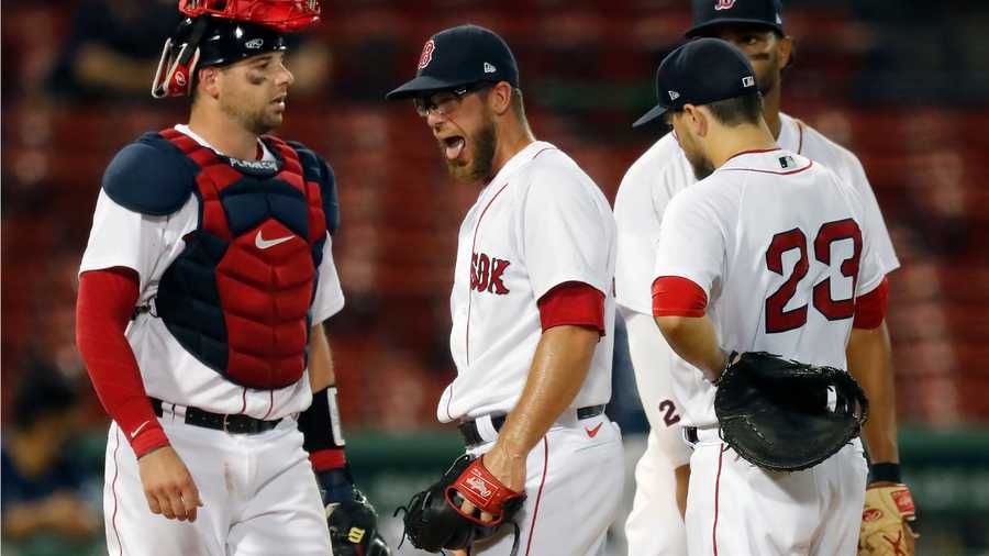 Boston Red Sox's Marcus Walden, center, reacts between teammates Kevin Plawecki, left, Xander Bogaerts, behind, and Michael Chavis (23) as manager Ron Roenicke comes to the mound for a pitching change during the fifth inning of a baseball game against the Tampa Bay Rays, Monday, Aug. 10, 2020, in Boston. (AP Photo/Michael Dwyer)