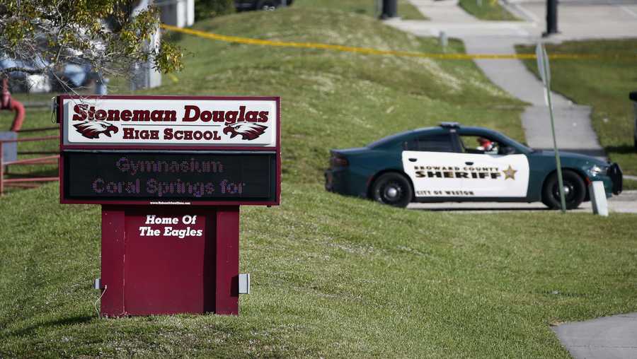 FILE- Law enforcement officers block off the entrance to Marjory Stoneman Douglas High School  Feb. 15, 2018 in Parkland, Fla., following a deadly shooting at the school. The families of most of those killed in the 2018 Florida high school massacre have settled their lawsuit against the federal government. Sixteen of the 17 killed at Marjory Stoneman Douglas High in Parkland had sued over the FBI’s failure to stop the gunman even though it had received information he intended to attack. The settlement reached Monday, Nov. 22, 2021 is confidential. (AP Photo/Wilfredo Lee, File)