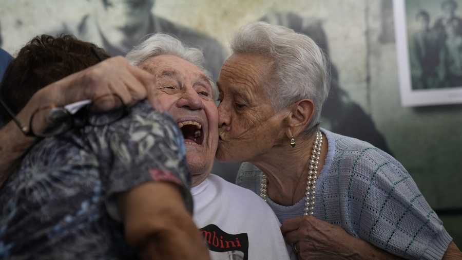 Retired American soldier Martin Adler, center, receives a kiss by Mafalda, right, and Giuliana Naldi that he saved during a WWII, at Bologna's airport, Italy, Monday, Aug. 23, 2021.